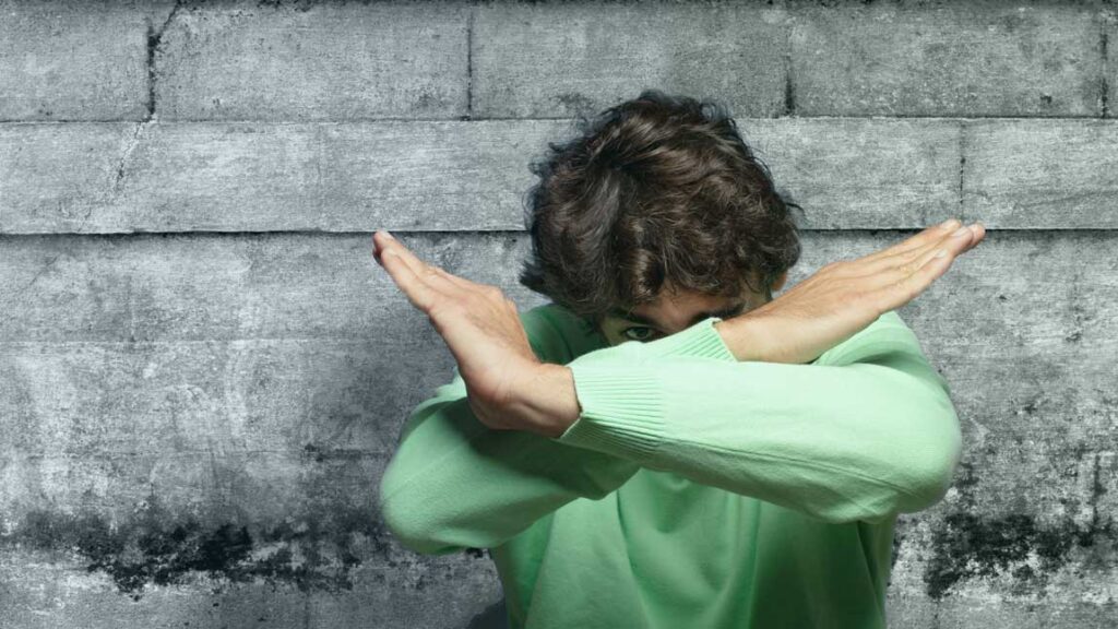 Jemand verschrenkt seine Arme vor dem Gesicht